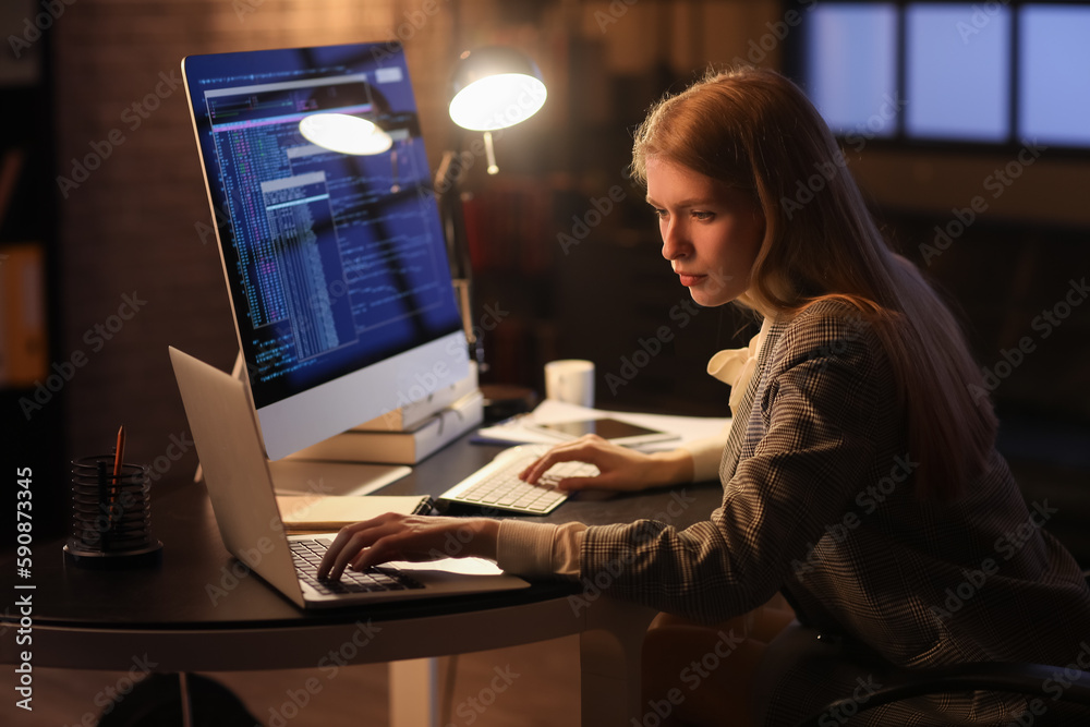 Female programmer working with laptop in office at night Female programmer working with laptop in office at night