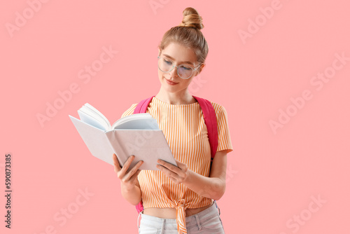 Female student reading book on pink background
