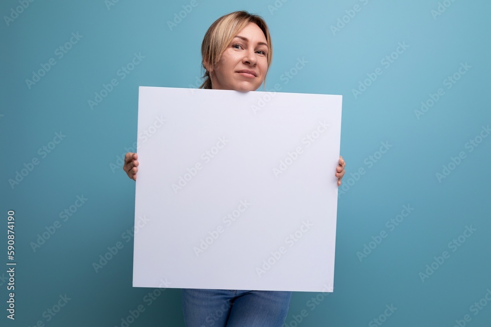 attractive blond woman holding a sheet of paper with a mocap for advertising on a purple background attractive blond woman holding a sheet of paper with a mocap for advertising on a purple background