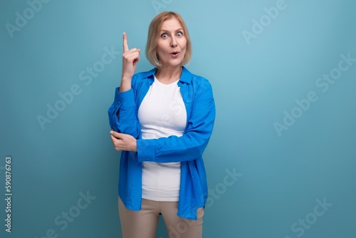 portrait of a blond attractive middle-aged woman in a casual stylish shirt on a blue background with copy space