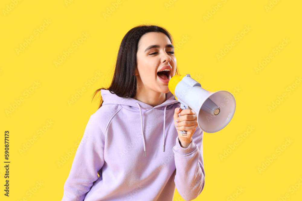 Young woman with megaphone on yellow background Young woman with megaphone on yellow background