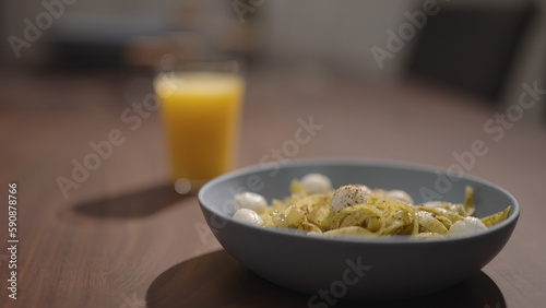 pesto fettuccine with mozzarella in blue bowl on walnut table