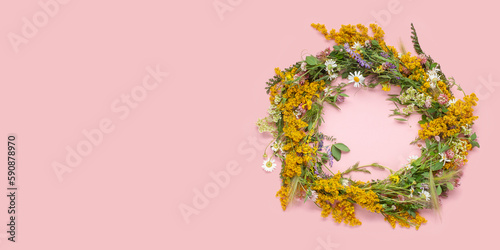 Beautiful wreath of wild flowers , typical Scandinavian midsummer decoration concept. Pink background. Top view. Copy space photo