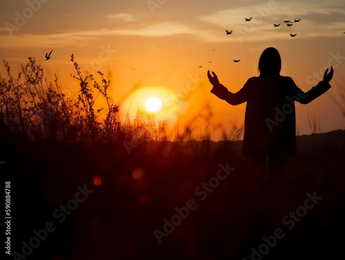 Silhouette of a woman open hand in the field of grass at the sunset thanking god, worshiping, praying to god, inspiration, resurrection hope and concept.