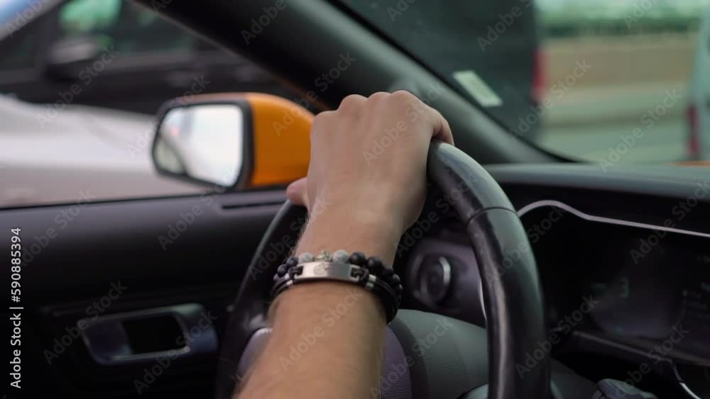 Orange convertible car driving in a city road in sunny summer day. Inside cabin - driver, steering wheel and dashboard. Man hand on steer. Orange convertible car driving in a city road in sunny summer day. Inside cabin - driver, steering wheel and dashboard. Man hand on steer.