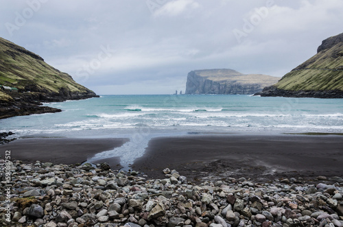 Beach in Tjornuvik, small charming fishing village in Streymoy, Faroe Islands, Northern Europe, view to Risin og Kellingin, big waves on the sea during the rainy day photo