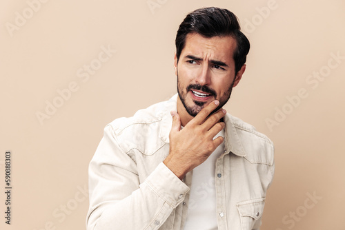 Portrait of a stylish man dissatisfied and angry screaming on a beige background in a white t-shirt looking at the camera, fashionable clothing style, copy space, space for text