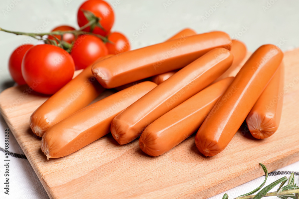 Wooden board with tasty sausages on light background, closeup Wooden board with tasty sausages on light background, closeup