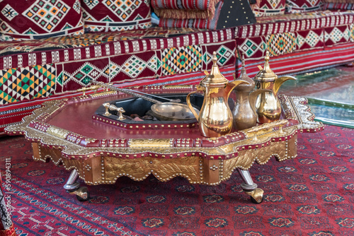 Traditional arabic coffee jugs or qahwa in Dubai with table and couch on oriental carpet with hot coals photo