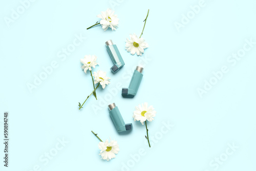 Asthma inhalers with daisy flowers on blue background