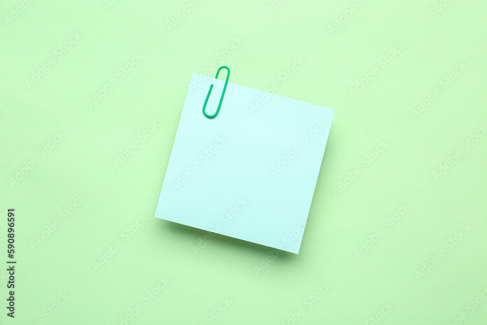 Sticky note with paper clip on green background Sticky note with paper clip on green background