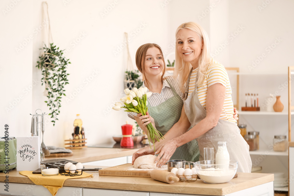 Young woman greeting her mother with tulips in kitchen