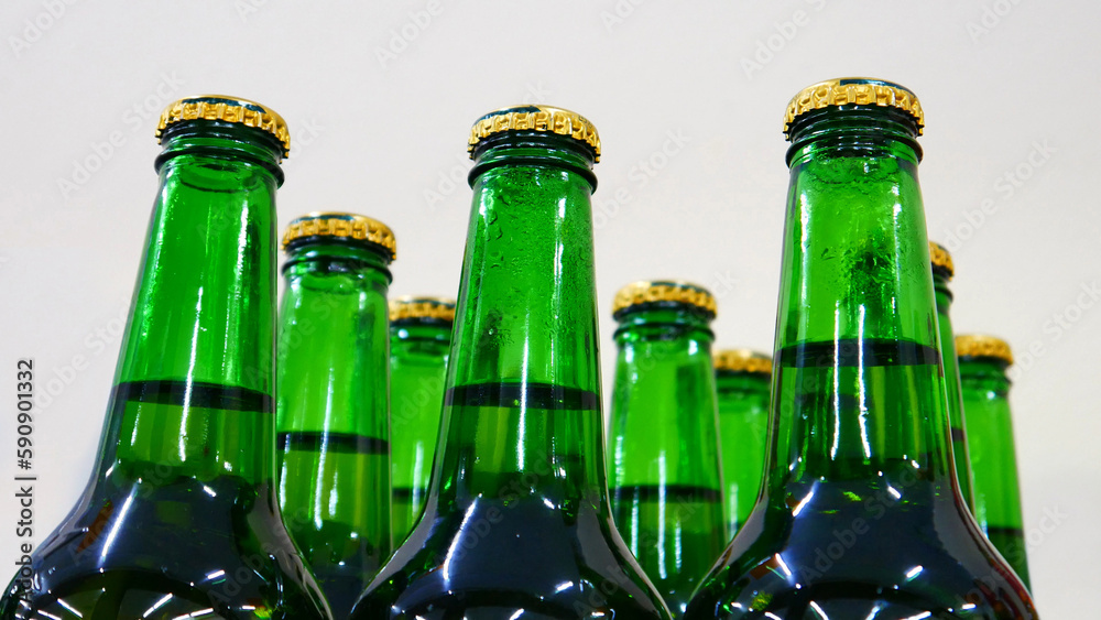 Close-up of many beautiful green glass bottles of beer with golden caps on a store shelf Close-up of many beautiful green glass bottles of beer with golden caps on a store shelf