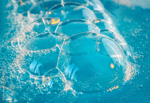 Texture of soap bubbles in close up. Bubble bath. Gel for washing or washing hands.Blue background with bursting bubbles