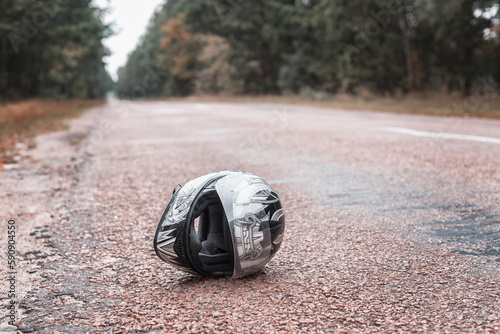 A biker\'s helmet lies on the road. A motorcycle helmet is lying on a wet street. The concept of a traffic accident, an accident with a motorcycle.