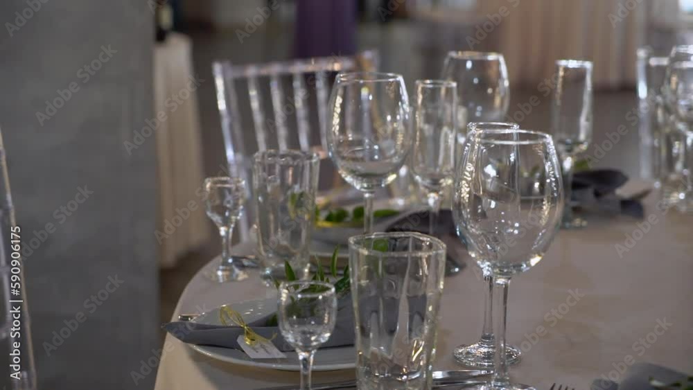 Served tables for a holiday in a restaurant. Glasses, plates, cutlery, napkins. Wedding decor, celebration dinner or party, reception indoors. No food. Decorated with flowers. Served tables for a holiday in a restaurant. Glasses, plates, cutlery, napkins. Wedding decor, celebration dinner or party, reception indoors. No food. Decorated with flowers.