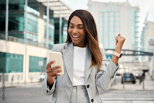 Foto African American joyful trader business woman with cellphone app, rejoices in the news reads from the smart phone stock good news