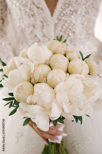 Beautiful white wedding bouquet of peonies in the hands of the bride