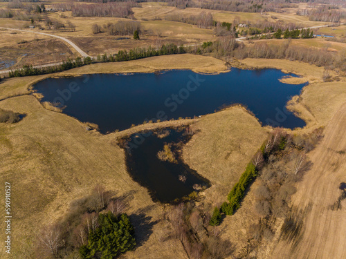 Aerial photo of deep blue lake in middle of field and yellow grass