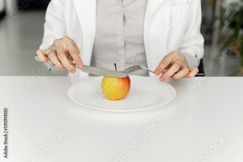 apple in a white plate. healthy diet. nutritionist doctor cuts an apple. proper nutrition.