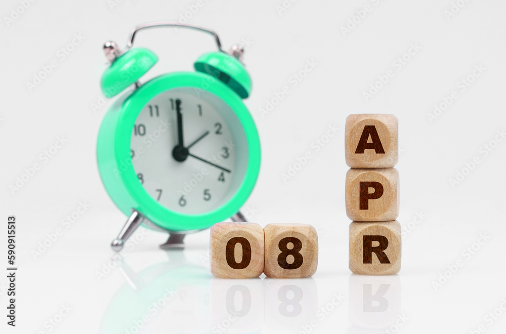 On a white background there is an alarm clock and a calendar with the inscription - April 8 On a white background there is an alarm clock and a calendar with the inscription - April 8