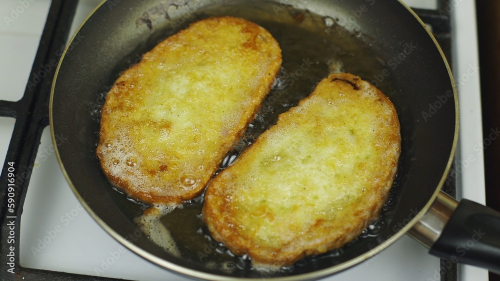 Cooking bread in an egg. Fry in oil in a pan. White stove, cooking breakfast. Black frying pan. There is a lot of fat in the pan. Fatty food, a lot of cholesterol. Fried croutons for breakfast