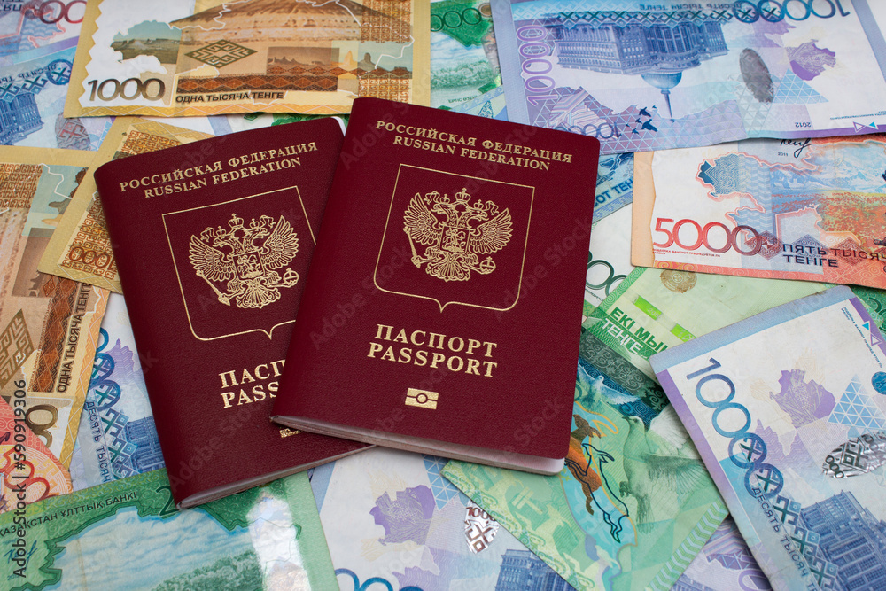 Fototapeta premium Russian biometric red passport. Modern multicolored cash paper banknotes of Republic of Kazakhstan. Kazakh money to pay for purchases, credit, debt. Concept of salary, tourism, travel. 5000 tenge. 