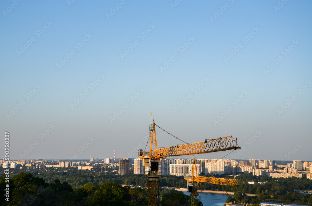 Yellow tower construction crane against a urban background. Industry new building business concept, city development
