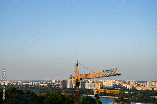 Yellow tower construction crane against a urban background. Industry new building business concept, city development