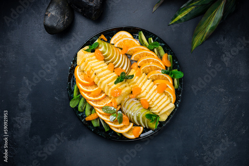 Fruit plate with oranges, pineapples, pears, kiwi, tangerines and mint.