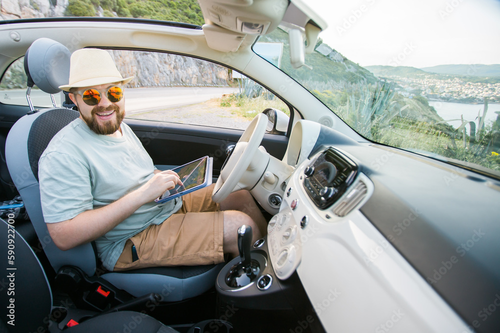 Naklejka premium Hipster man looking on location navigation map in car, tourist traveler driving and hold in male hands europe cartography, view and plan tourist way road, trip in transportation cabriolet auto