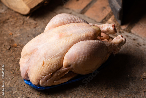 Raw shop chicken carcass on stone background. Whole chicken, preparation for cooking.