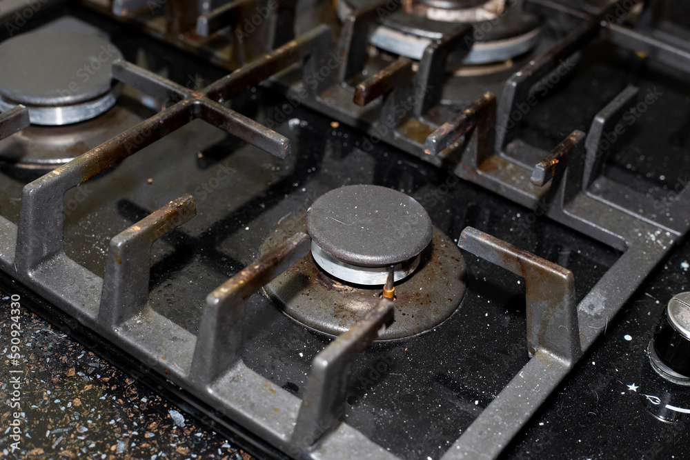 Gas stove with black tempered glass surface with a layer of dust and dirt from cooking Gas stove with black tempered glass surface with a layer of dust and dirt from cooking