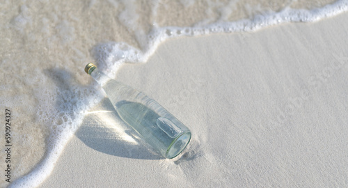 Foto Glass bottle of pure water on the white sand on the Maldives beach