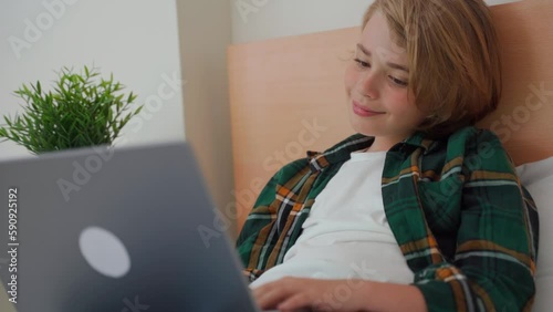 Smart caucasian middle School child boy using laptop. Child typing on the keyboard. Play video game.Online tutor teaching digital class, web lesson on computer at home. Virtual education. E-education