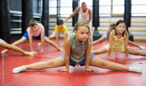 Little preteen girl doing splits during training at sport class indoor