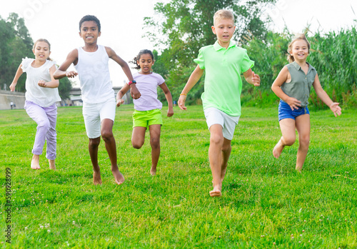 Portrait of five smiling kids who are running in race and laughing in park