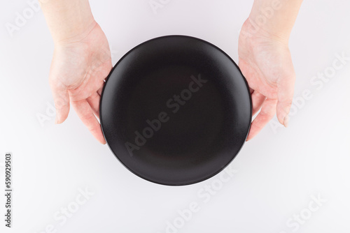 female hands hold an empty black plate. Space for food advertising