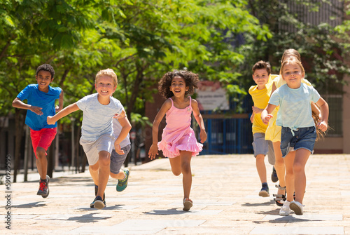 Fototapeta Naklejka Na Ścianę i Meble -  Group of joyful children running down the summer city street