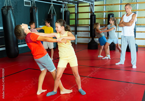 Children practicing self defence technique in pairs at gym