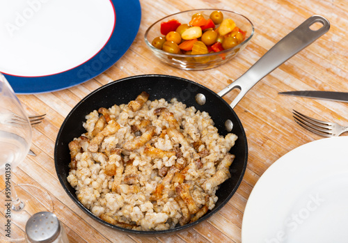 Delicious barley porridge served with pieces of fried lard on plate