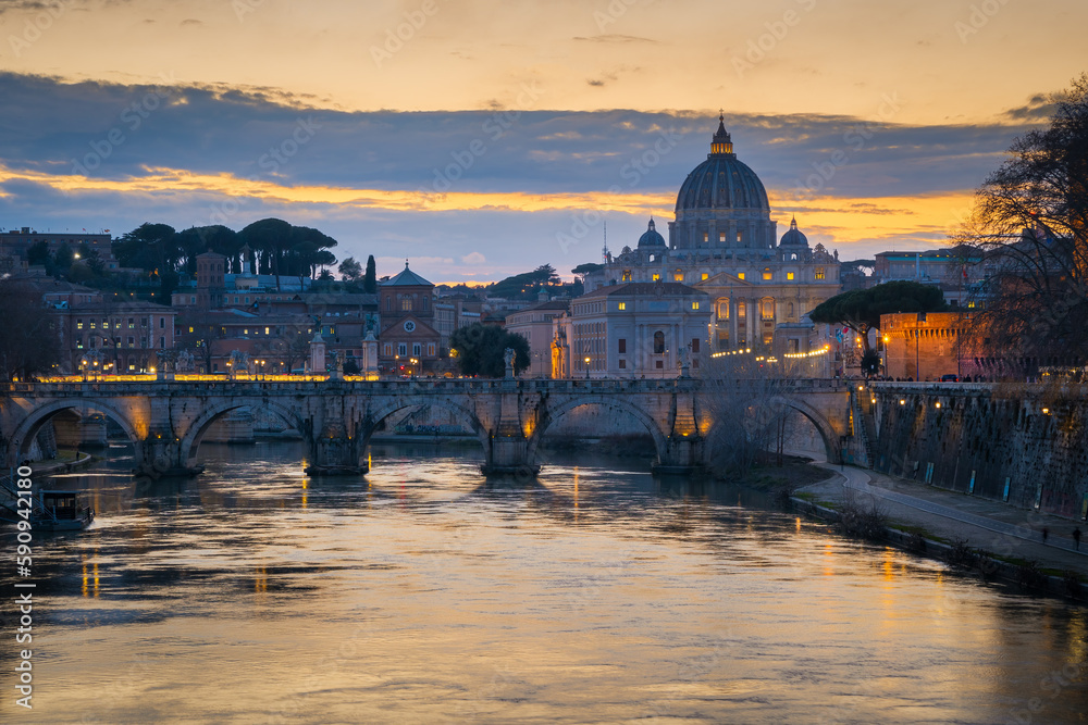 Cityscape with Sant Angelo bridge and St. Peter's cathedral at sunset with city lights in Rome, Italy