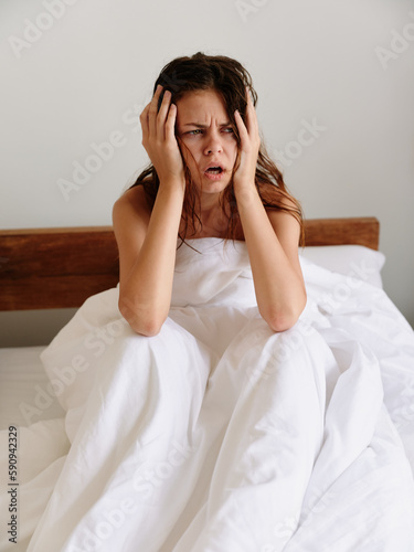 Woman sadness sits on the bed in the bedroom and covers her body with a blanket, early awakening, sleepy appearance, hangover, fatigue and depression, emotional burnout