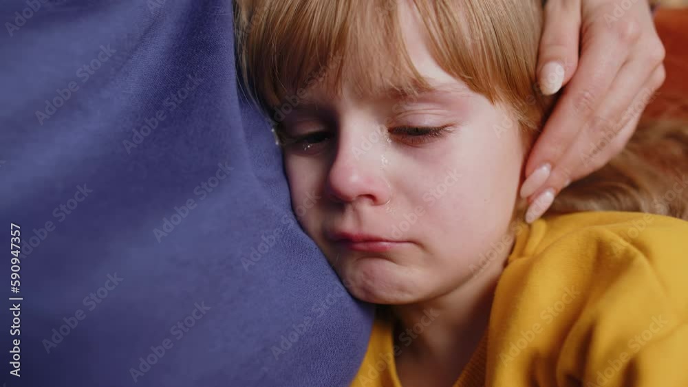 Close-up portrait of upset child little girl kid crying with tears flowing down on her cheek, toddler lies on mother at home. Mom hugs, embrace, takes pity on her daughter. Quarrel, bullying at school Close-up portrait of upset child little girl kid crying with tears flowing down on her cheek, toddler lies on mother at home. Mom hugs, embrace, takes pity on her daughter. Quarrel, bullying at school