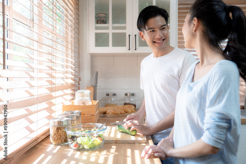 Happy Asian couple having fun in kitchen while preparing food.