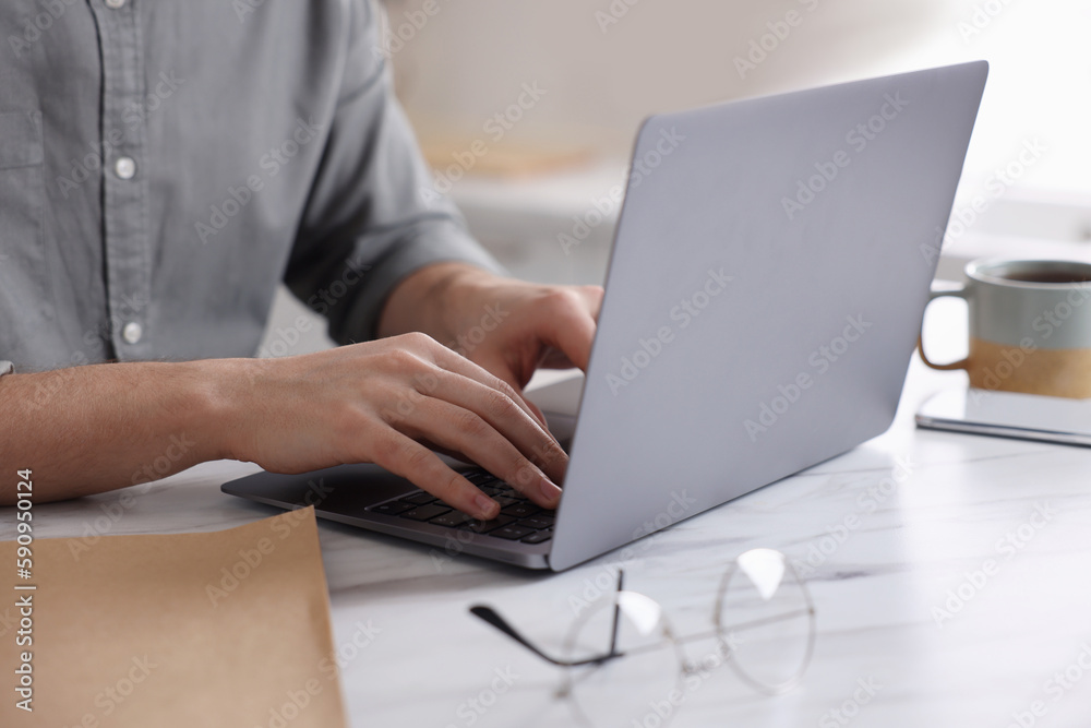 Man working on laptop at white marble table indoors, closeup Man working on laptop at white marble table indoors, closeup