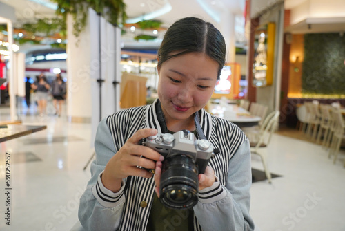 Young female photographer looking at photos on mirrorless camera.