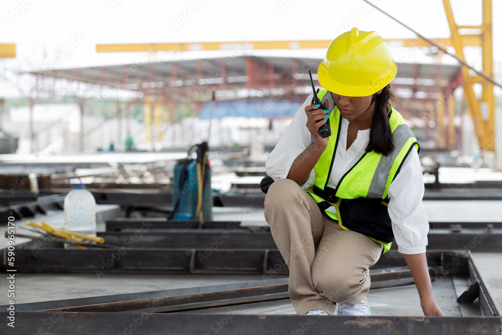 Young woman engineer using radio command with worker in construction site, architect or contractor speak to radio for control and planning development structure at precast factory, industrial concept. Young woman engineer using radio command with worker in construction site, architect or contractor speak to radio for control and planning development structure at precast factory, industrial concept.