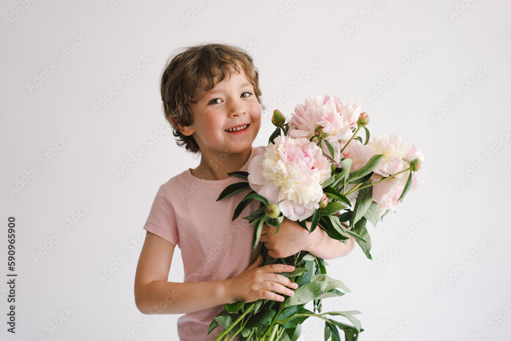 Cheerful happy child with Peonys bouquet. Smiling little boy on white background. Mother's Day. Love and romantic concept Cheerful happy child with Peonys bouquet. Smiling little boy on white background. Mother's Day. Love and romantic concept