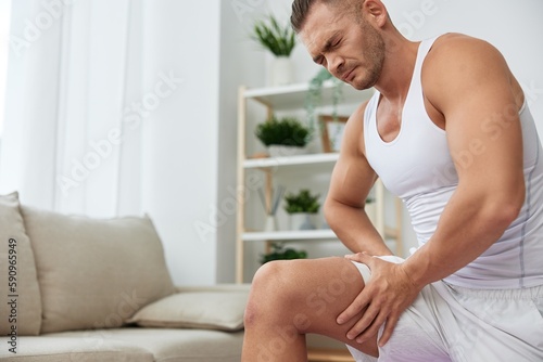 Man sports pain in the side and leg during a workout at home, pumped up man sports, the concept of health without injuries and sprains muscles and ligaments of the body